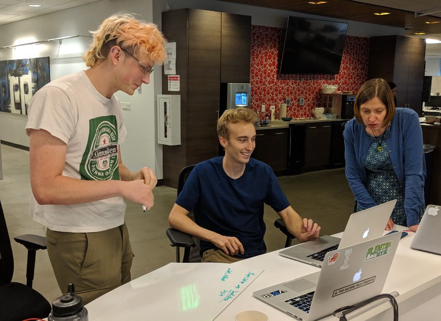 Two mentees showing the newest team member what they know